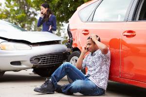 crash victim on phone by damaged car