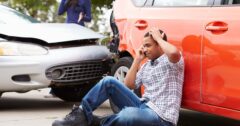 crash victim on phone by damaged car