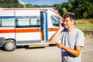 man standing by ambulance making phone call