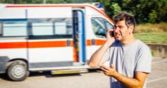 man standing by ambulance making phone call