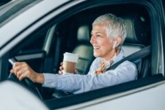 Women driving with headphones and coffee.