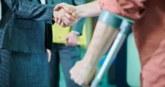 side view close up of lawyer shaking hands with man leaning into arm crutch