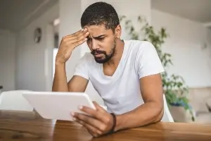 young black man looking at computer tablet looking upset and confused