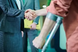 side view close up of lawyer shaking hands with man leaning into arm crutch