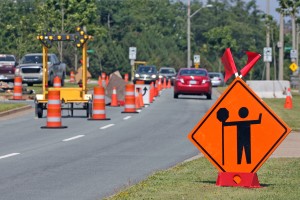 image of a road work construction zone with orange cones and construction signs placed along the road