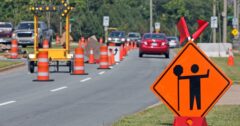 image of a road work construction zone with orange cones and construction signs placed along the road
