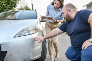 Two people are evaluating the damages of car accident.